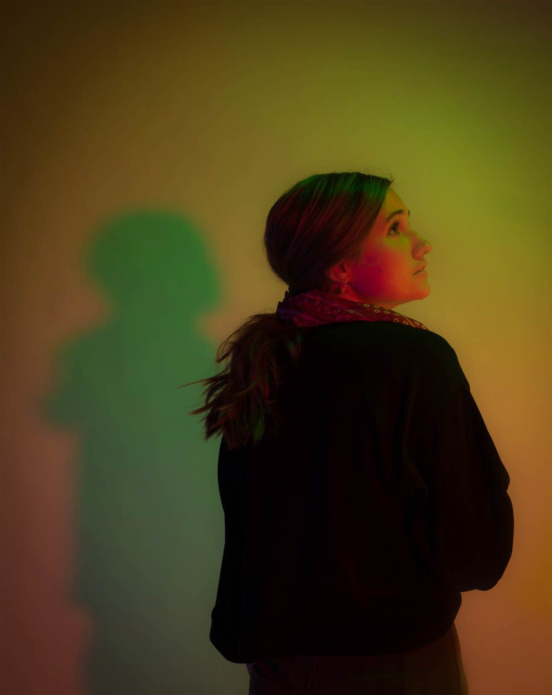 A woman with back to the camera, looking up, in green lighting.