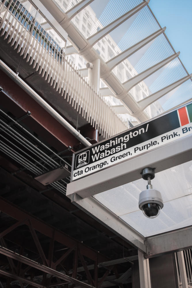 Photo looking up at a train stop sign. Sign reads "Washington/Wabach" as white text on black background. Below, black text on white background reads "cta Orange, Green, Purple, Pink, Br"