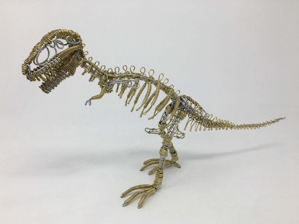 A miniature tyrannosaurus rex skeleton made of copper and silver wire.