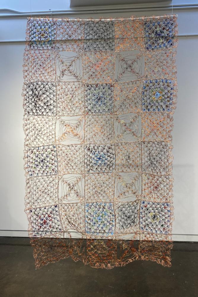 Another quilt of granny squares made of green, blue, and copper colored wire.